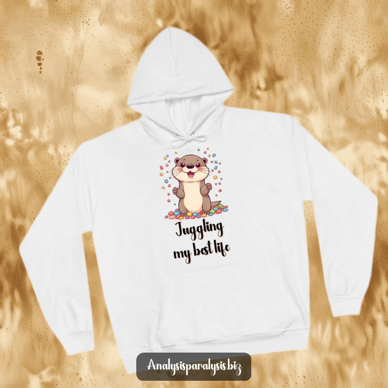 Funny hoodie featuring a cheerful otter juggling many tiny, colorful pebbles, a cozy and humorous garment for all.